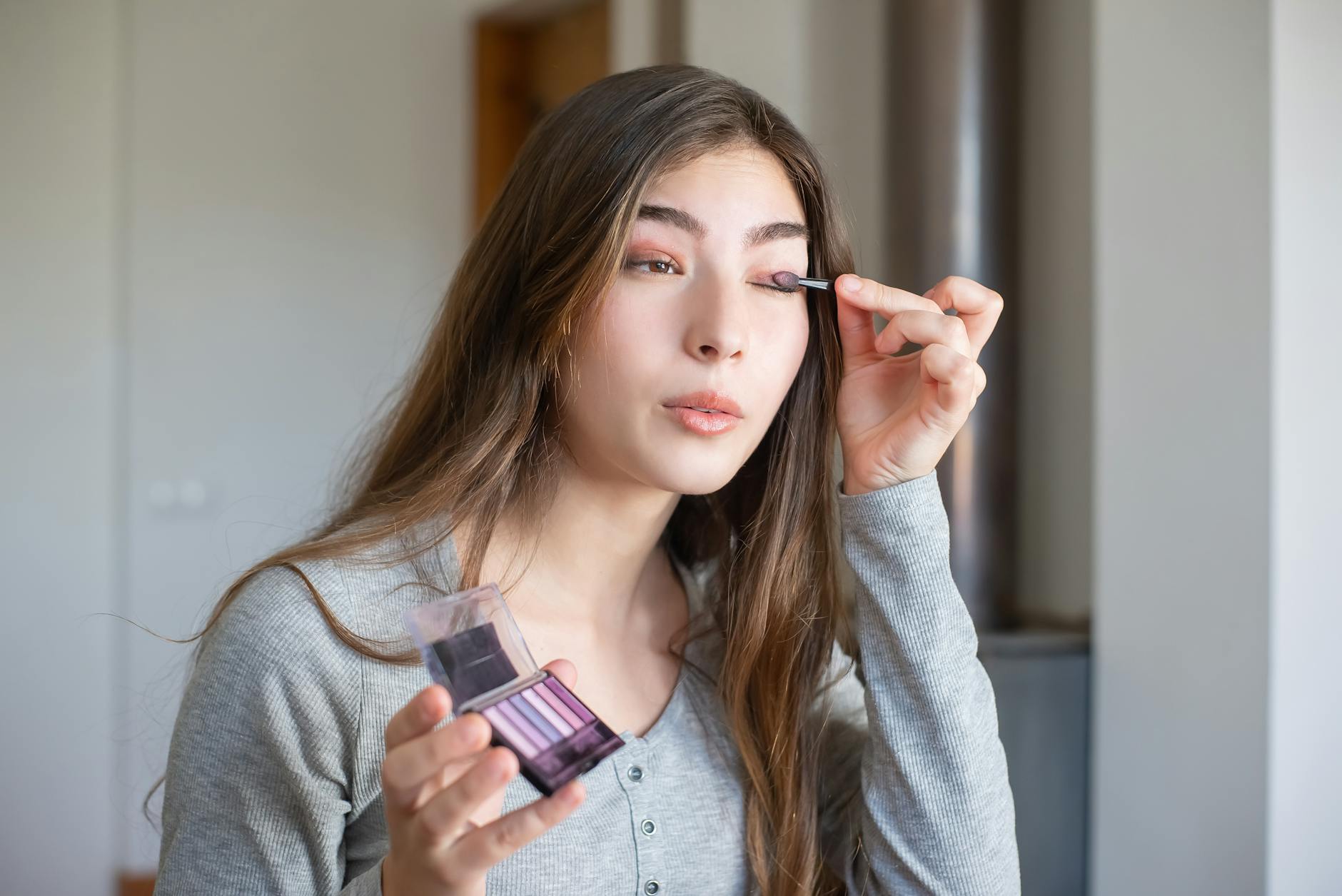 Azjatka nakłada cienie do powiek podczas codziennego makijażu indoors