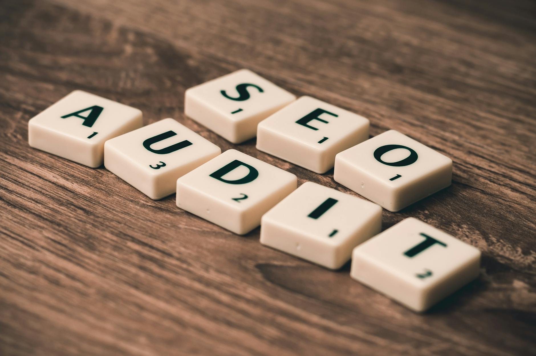 Drewniane płytki Scrabble układające się w napis SEO Audit na blacie