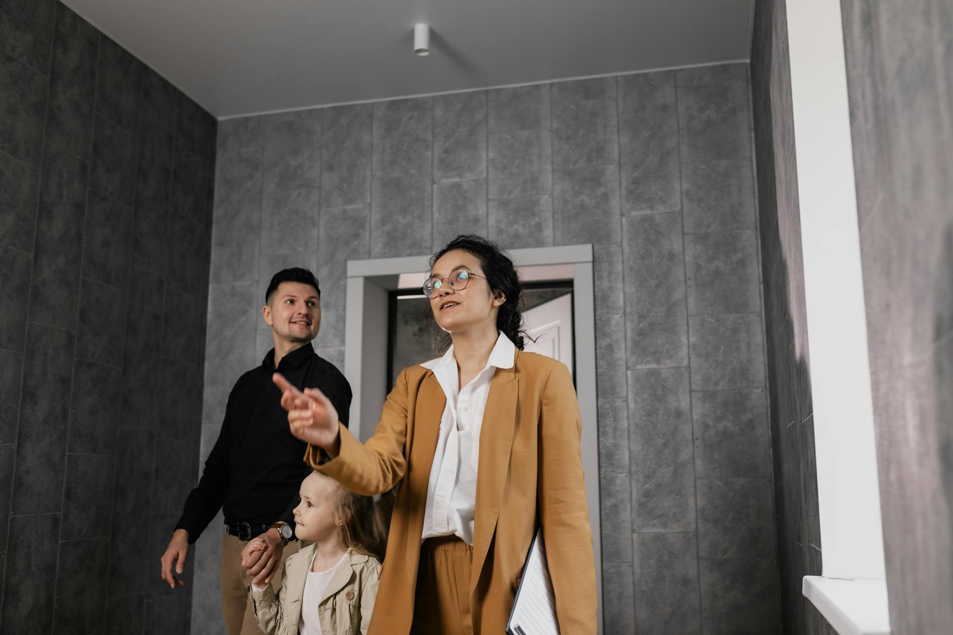 Rodzina zwiedzająca nowoczesne wnętrze domu z agentem nieruchomości