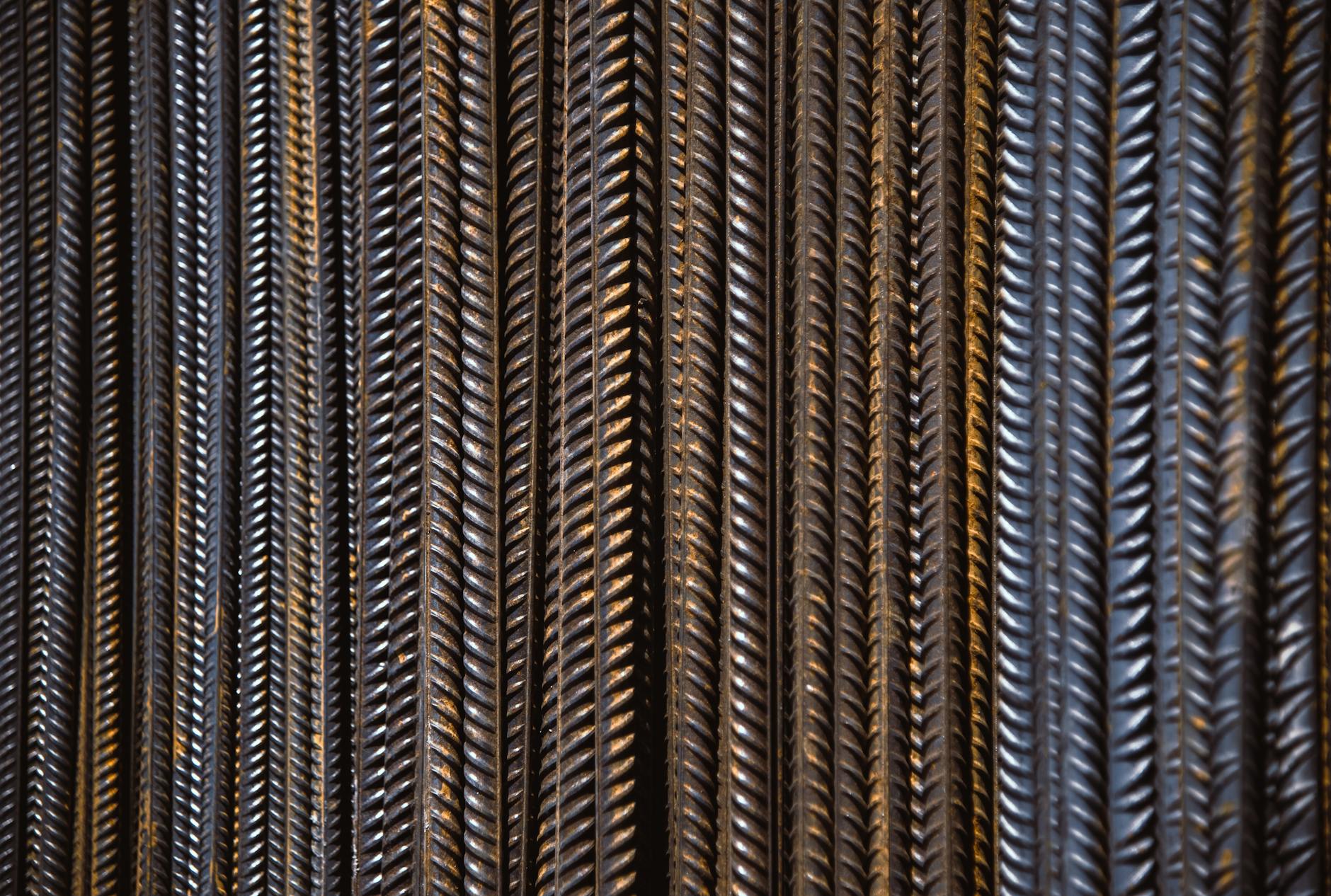 Zbliżenie pionowo ustawionych prętów zbrojeniowych z wyraźnym żebrowaniem