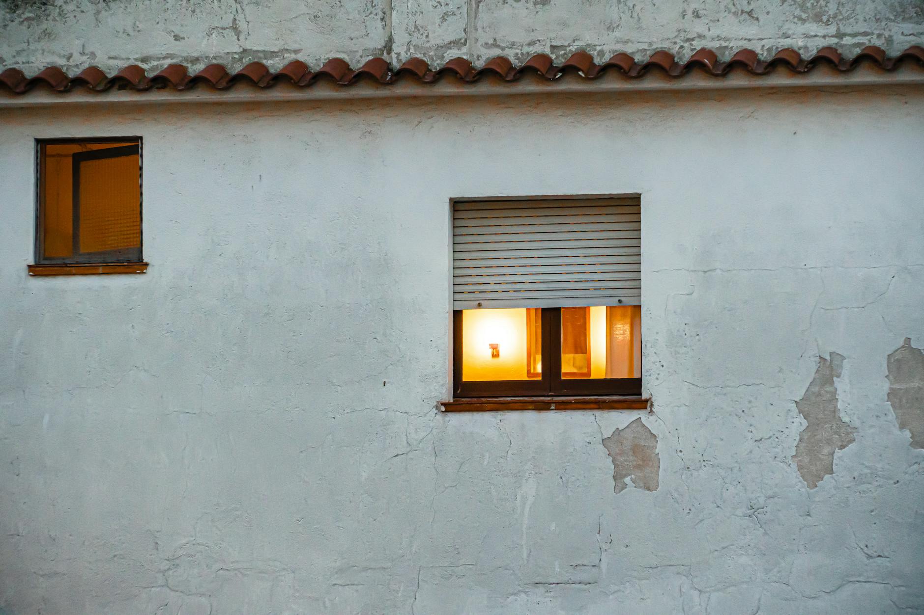 Elewacja domu z oświetlonymi oknami i fakturą tynku zewnętrznego