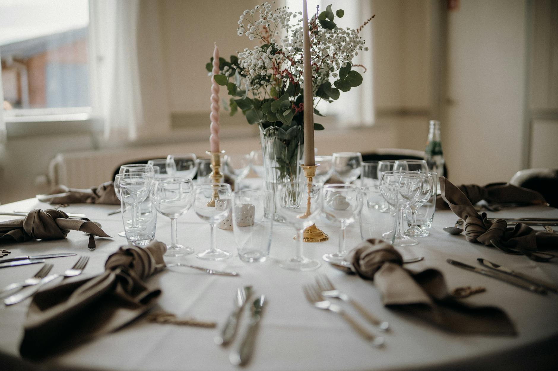 Kameralny stół weselny z kwiatami, świecami i elegancką zastawą