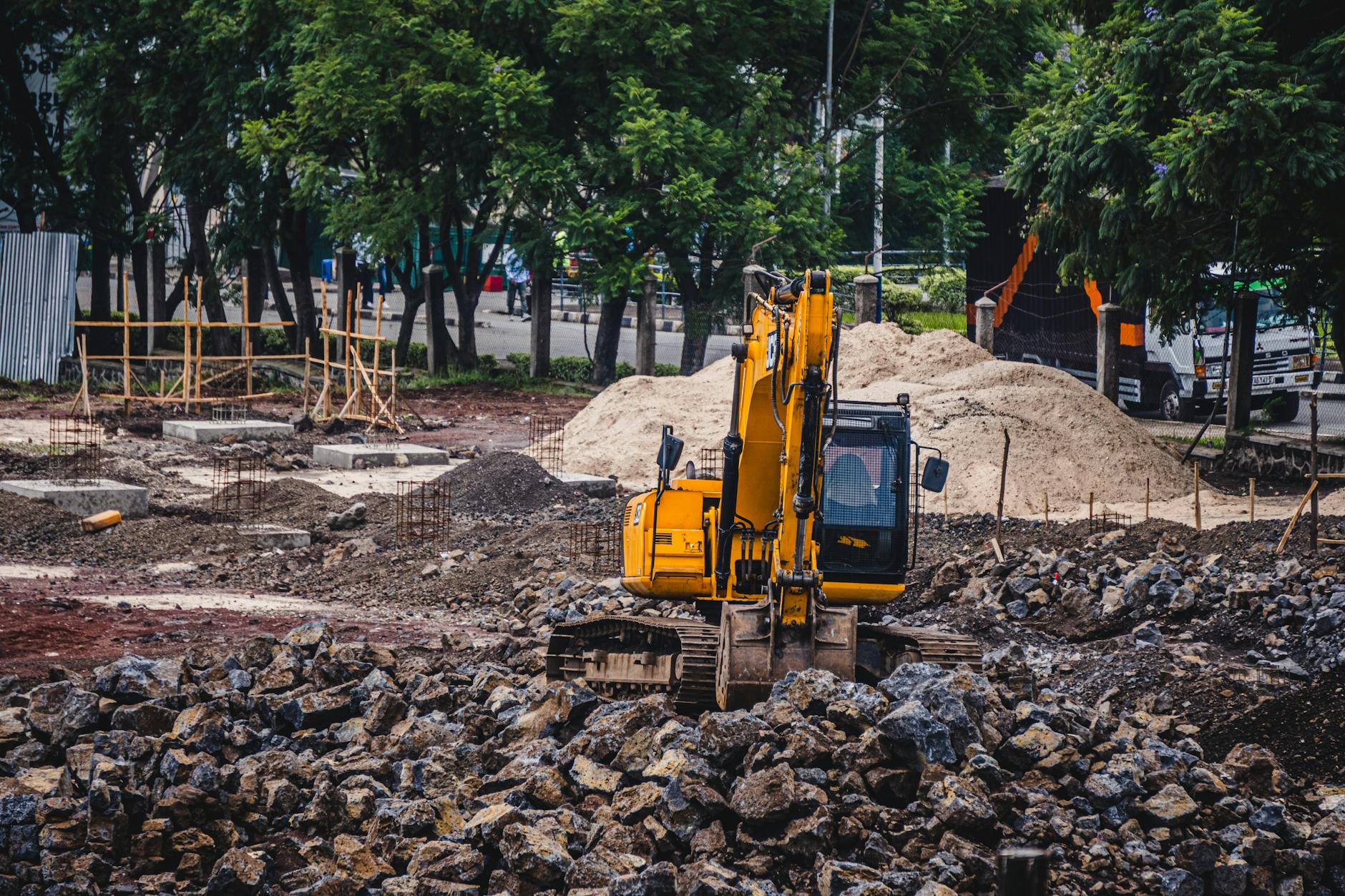 Roboty ziemne i fundamenty: jak przewidzieć koszty niespodzianek w gruncie Koparka wykonująca roboty ziemne na miejskim placu budowy