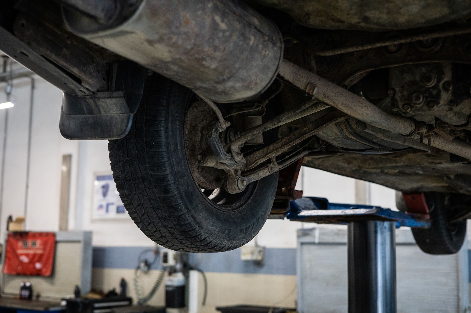 Mechanik ogląda zawieszenie busa od spodu na podnośniku w warsztacie