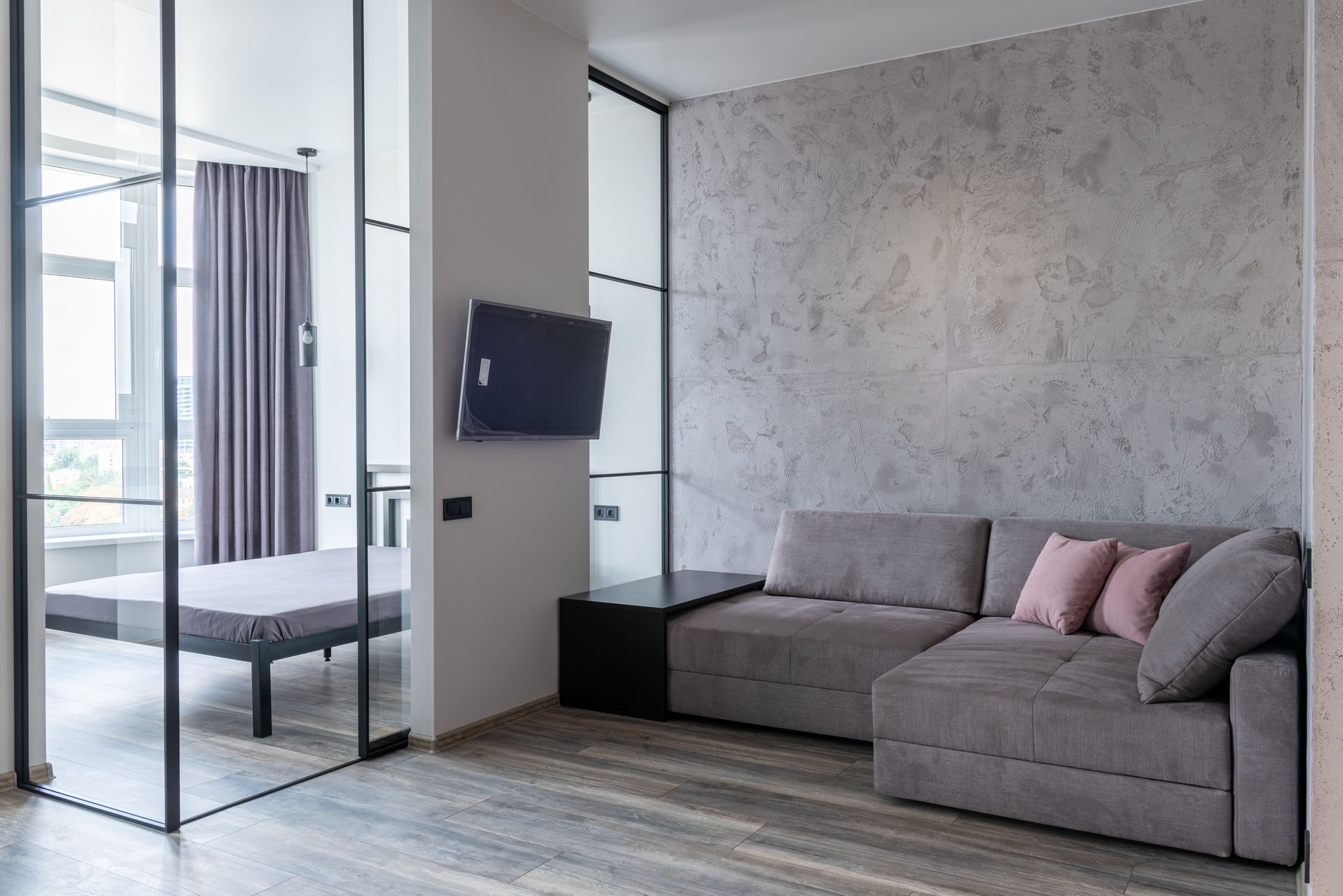 Nowoczesny salon z sofą, poduszkami i przeszkloną ścianą